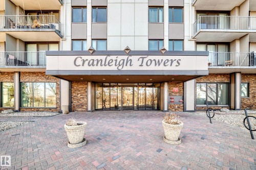 "Cranleigh Towers" building entrance featuring a stone facade, glass double doors, ground-level windows, and a paved brick walkway - 405 10135 Saskatchewan Drive Nw, Edmonton, AB - Outdoor