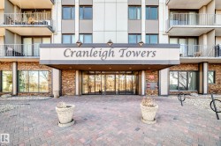 "Cranleigh Towers" building entrance featuring a stone facade, glass double doors, ground-level windows, and a paved brick walkway - 