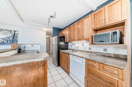 Kitchen featuring wood cabinetry, white tile flooring, and a stone-finish countertop - 405 10135 Saskatchewan Drive Nw, Edmonton, AB - Indoor Photo Showing Kitchen