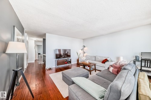 Spacious living area featuring wood-finish flooring, white walls, and a textured ceiling - 601 10135 Saskatchewan Drive Nw, Edmonton, AB - Indoor Photo Showing Living Room