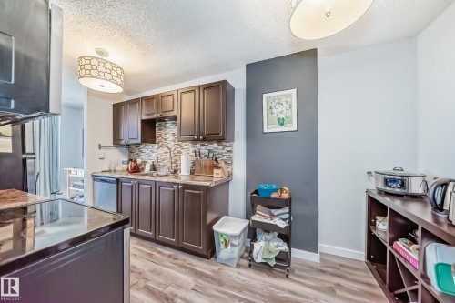 Kitchen featuring wood-finish flooring, dark wood cabinetry, a mosaic tile backsplash, and stainless steel appliances - 601 10135 Saskatchewan Drive Nw, Edmonton, AB - Indoor Photo Showing Kitchen
