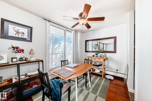 Room featuring wood-finish flooring, a ceiling fan with integrated lighting, and a sliding glass door leading to a balcony with a metal railing - 601 10135 Saskatchewan Drive Nw, Edmonton, AB - Indoor Photo Showing Dining Room