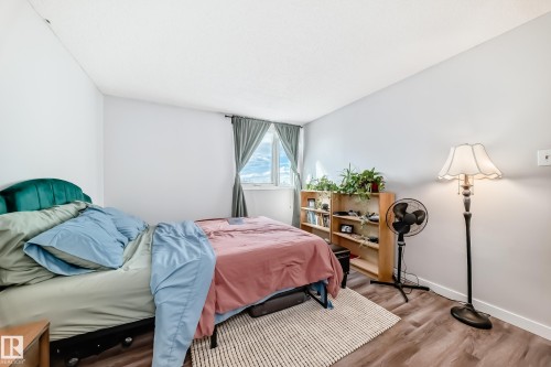 Bedroom featuring light-colored walls, wood-finish flooring, and a single window with curtain rods - 601 10135 Saskatchewan Drive Nw, Edmonton, AB - Indoor Photo Showing Bedroom