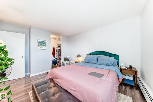 Spacious room featuring wood-finish flooring, light grey walls, and an open closet area - 601 10135 Saskatchewan Drive Nw, Edmonton, AB - Indoor Photo Showing Bedroom
