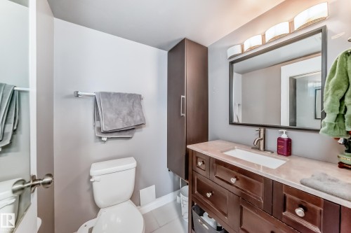 Bathroom featuring a dark wood-finish vanity with a light countertop, a rectangular undermount sink, and a framed wall mirror - 601 10135 Saskatchewan Drive Nw, Edmonton, AB - Indoor Photo Showing Bathroom