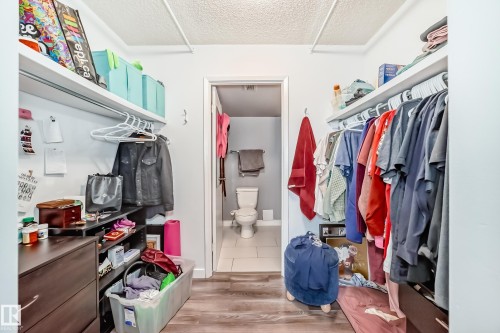 Walk-in closet featuring wood-finish flooring, built-in shelving, and hanging rods - 601 10135 Saskatchewan Drive Nw, Edmonton, AB - Indoor With Storage