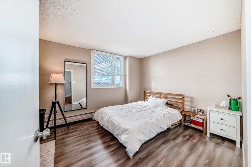 Bedroom featuring wood-finish flooring, a large window with horizontal blinds, and neutral wall paint - 601 10135 Saskatchewan Drive Nw, Edmonton, AB - Indoor Photo Showing Bedroom