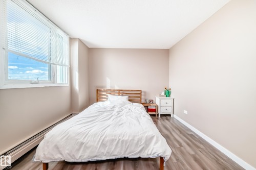 Room featuring wood-finish flooring, a large window with blinds, and light-toned walls - 601 10135 Saskatchewan Drive Nw, Edmonton, AB - Indoor Photo Showing Bedroom