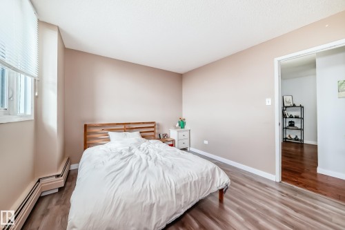 Spacious room featuring wood-finish flooring, a window with horizontal blinds, and a neutral wall color - 601 10135 Saskatchewan Drive Nw, Edmonton, AB - Indoor Photo Showing Bedroom