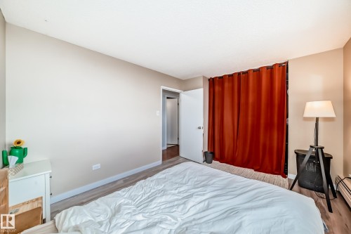 Bedroom featuring light wood-finish flooring, neutral wall tones, and a closet with a full-length curtain closure - 601 10135 Saskatchewan Drive Nw, Edmonton, AB - Indoor Photo Showing Bedroom