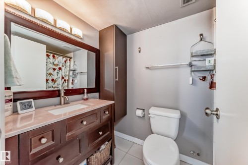 Bathroom featuring a wood-finish vanity with an integrated sink and light-toned countertop - 601 10135 Saskatchewan Drive Nw, Edmonton, AB - Indoor Photo Showing Bathroom