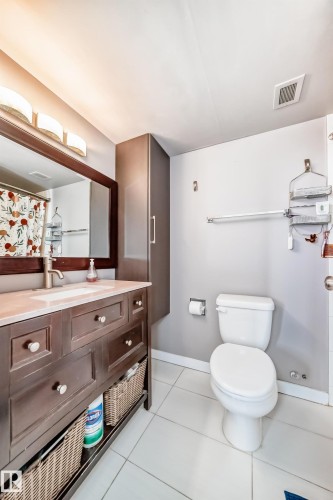 Bathroom featuring a dark wood-finish vanity with countertop, undermount sink, and wall-mounted mirror - 601 10135 Saskatchewan Drive Nw, Edmonton, AB - Indoor Photo Showing Bathroom