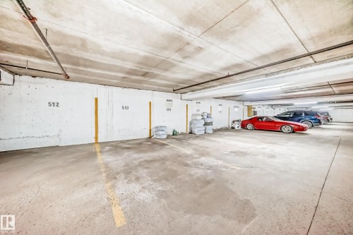 Underground parking garage featuring concrete flooring, overhead lighting, exposed ceiling beams, and numbered parking spaces - 601 10135 Saskatchewan Drive Nw, Edmonton, AB - Indoor Photo Showing Garage