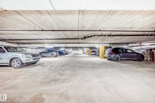 Underground parking garage featuring concrete flooring and ceiling, exposed overhead piping, and integrated lighting - 601 10135 Saskatchewan Drive Nw, Edmonton, AB - Indoor Photo Showing Garage