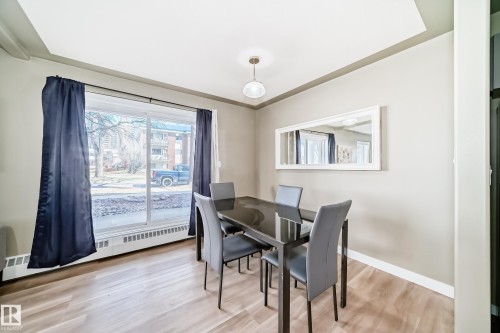 Dining area with wood-finish flooring and a large sliding glass door - 101 10827 85 Avenue Nw, Edmonton, AB - Indoor Photo Showing Dining Room