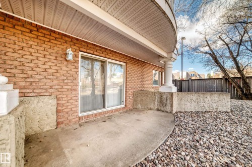 Brick exterior with a concrete patio, sliding glass door, and white architectural columns - 101 10827 85 Avenue Nw, Edmonton, AB - Outdoor With Exterior
