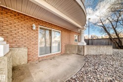 Brick exterior with a concrete patio, sliding glass door, and white architectural columns - 