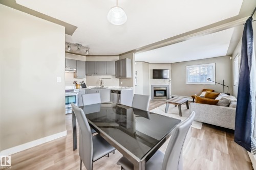 Open-concept dining area featuring wood-finish flooring, a contemporary overhead light fixture, and a clear line of sight to the kitchen and living room - 101 10827 85 Avenue Nw, Edmonton, AB - Indoor With Fireplace