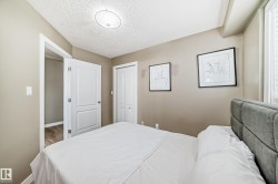 Bedroom featuring soft neutral wall paint, a white paneled door, bi-fold closet doors, and wood-finish flooring visible through the doorway - 