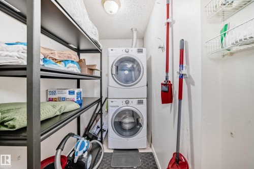 Dedicated laundry area featuring a stacked washer and dryer unit - 101 10827 85 Avenue Nw, Edmonton, AB - Indoor Photo Showing Laundry Room