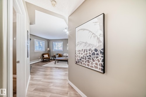 Bright interior space featuring wood-finish flooring, two windows, and neutral wall tones - 101 10827 85 Avenue Nw, Edmonton, AB - Indoor Photo Showing Other Room
