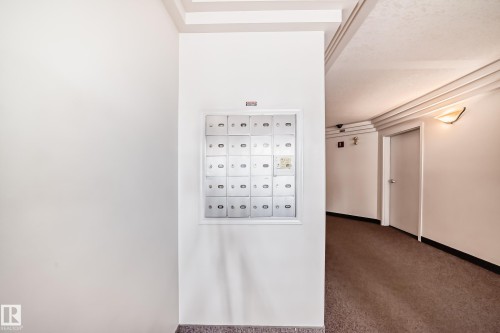 Wall-mounted mailboxes within a common area corridor featuring recessed lighting, a textured ceiling, and a wall sconce - 101 10827 85 Avenue Nw, Edmonton, AB - Indoor Photo Showing Other Room