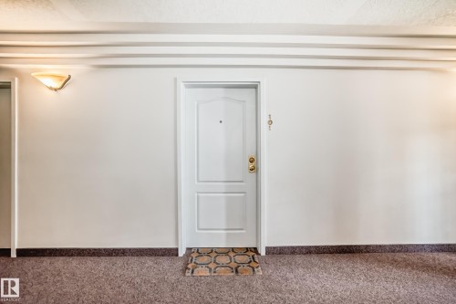 White paneled entry door with brass hardware and peep hole - 101 10827 85 Avenue Nw, Edmonton, AB - Indoor Photo Showing Other Room