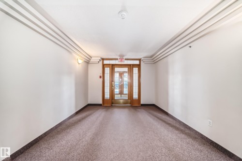 Entryway featuring a wood-framed glass door, complementary side panels, and sconce lighting - 101 10827 85 Avenue Nw, Edmonton, AB - Indoor Photo Showing Other Room