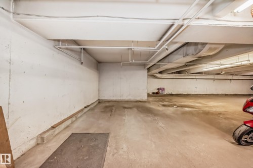 Subterranean parking area featuring concrete flooring and walls, exposed overhead utility lines, and fluorescent lighting - 101 10827 85 Avenue Nw, Edmonton, AB - Indoor Photo Showing Garage