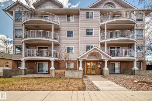 Multi-story building exterior featuring light-colored siding and a brick base - 101 10827 85 Avenue Nw, Edmonton, AB - Outdoor With Facade