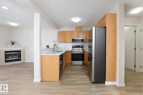 Kitchen featuring wood cabinetry, stainless steel appliances, white subway tile backsplash, and light-toned countertops - 55 14603 Miller Boulevard, Edmonton, AB - Indoor Photo Showing Kitchen