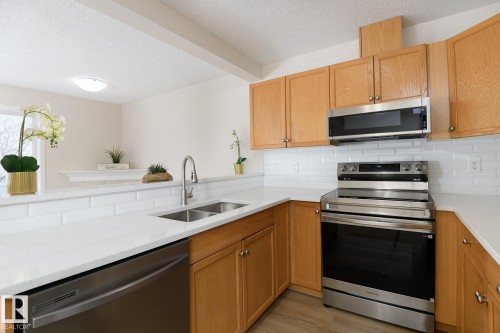 Modern kitchen featuring light wood cabinetry, a double basin stainless steel sink, white subway tile backsplash, and stainless steel appliances - 55 14603 Miller Boulevard, Edmonton, AB - Indoor Photo Showing Kitchen With Double Sink