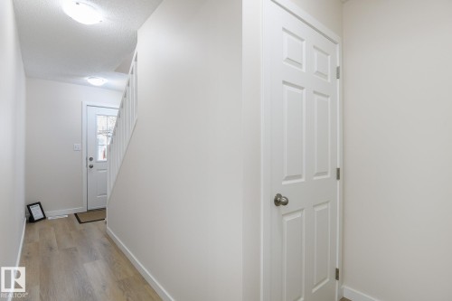 Entryway featuring wood-finish flooring, a six-panel interior door with brushed nickel hardware, and an overhead flush-mount light fixture - 55 14603 Miller Boulevard, Edmonton, AB - Indoor Photo Showing Other Room