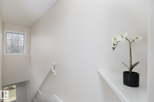 Stairwell featuring a grid-patterned window, white handrail, and light neutral wall finish - 55 14603 Miller Boulevard, Edmonton, AB - Indoor Photo Showing Other Room