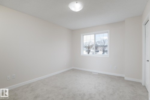 Bright interior room featuring a multi-pane window with white trim, light-colored carpeting, and a flush-mount ceiling light fixture - 55 14603 Miller Boulevard, Edmonton, AB - Indoor Photo Showing Other Room