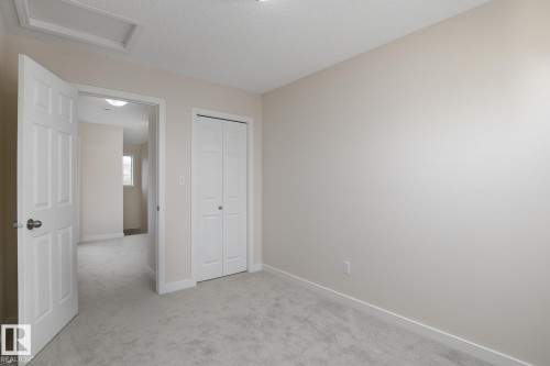 Carpeted room featuring neutral wall paint, white trim, and a bi-fold closet door - 55 14603 Miller Boulevard, Edmonton, AB - Indoor Photo Showing Other Room