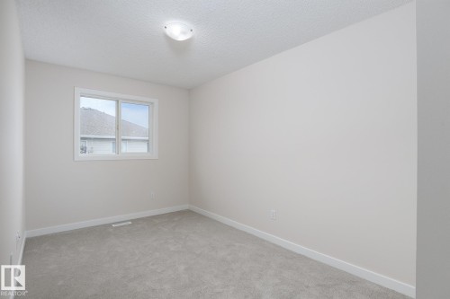 Neutral wall tones with white trim, grey carpeting, and a ceiling-mounted light fixture - 55 14603 Miller Boulevard, Edmonton, AB - Indoor Photo Showing Other Room