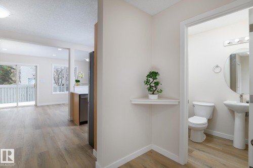 Light wood-finish flooring throughout, with a pedestal sink and toilet in the visible bathroom - 55 14603 Miller Boulevard, Edmonton, AB - Indoor Photo Showing Bathroom