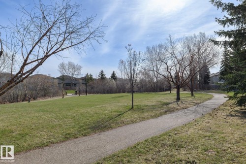 Paved pathway winding through a grassy park area with mature trees and distant residential structures - 55 14603 Miller Boulevard, Edmonton, AB - Outdoor With View