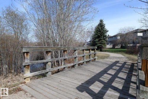 Wooden pedestrian bridge over a body of water with natural landscaping - 55 14603 Miller Boulevard, Edmonton, AB - Outdoor With Deck Patio Veranda