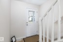 Entryway featuring a white paneled door with window inserts, light-colored walls, wood-finish flooring, and a white staircase with balusters - 55 14603 Miller Boulevard, Edmonton, AB  - Indoor Photo Showing Other Room 