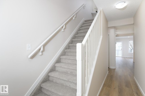 Carpeted staircase with white balusters and handrail - 55 14603 Miller Boulevard, Edmonton, AB - Indoor Photo Showing Other Room