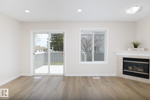 Living area featuring wood-finish flooring, recessed lighting, and a white mantel fireplace with a tile surround - 55 14603 Miller Boulevard, Edmonton, AB - Indoor Photo Showing Living Room With Fireplace