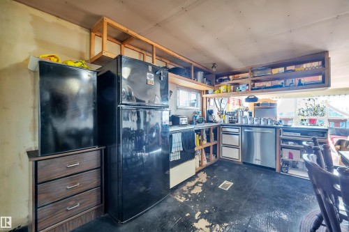 Kitchen featuring freestanding refrigerator, dishwasher, and open shelves - 21 Calmar Mobile Home Park, Calmar, AB - Indoor Photo Showing Other Room