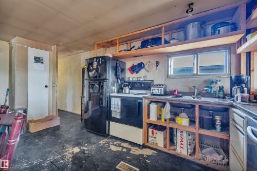 Kitchen with freestanding refrigerator, white electric stove, open shelves, and stainless steel dishwasher - 21 Calmar Mobile Home Park, Calmar, AB - Indoor Photo Showing Kitchen