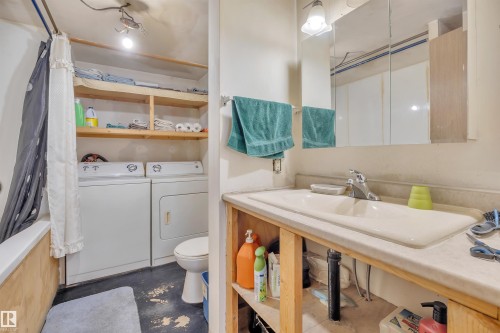 Full bathroom featuring washer and dryer, shower / bath combo with shower curtain, and concrete floors - 21 Calmar Mobile Home Park, Calmar, AB - Indoor Photo Showing Other Room