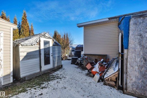 View of snowy exterior featuring a storage unit and a patio area - 21 Calmar Mobile Home Park, Calmar, AB - Outdoor With Exterior