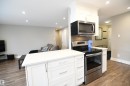 Solid surface counters with an undermount sink, contemporary white cabinetry, tile backsplash, ample pot lights, stainless appliance package, and an inviting, open layout - 206 8125 110 Street, Edmonton, AB  - Indoor Photo Showing Kitchen 