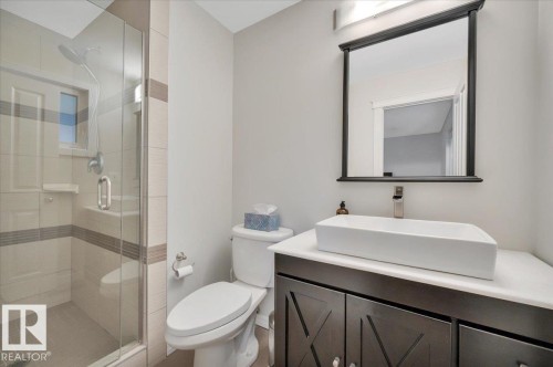3 piece featuring a glass-enclosed shower with tiled walls & a vanity with a rectangular vessel sink. - 705 Riddell Street, Edmonton, AB - Indoor Photo Showing Bathroom