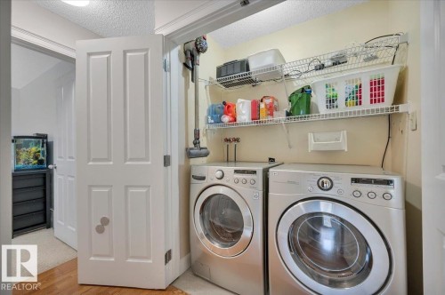 Main floor laundry area featuring front-loading washer and dryer units, with wire shelving providing storage space - 705 Riddell Street, Edmonton, AB - Indoor Photo Showing Laundry Room